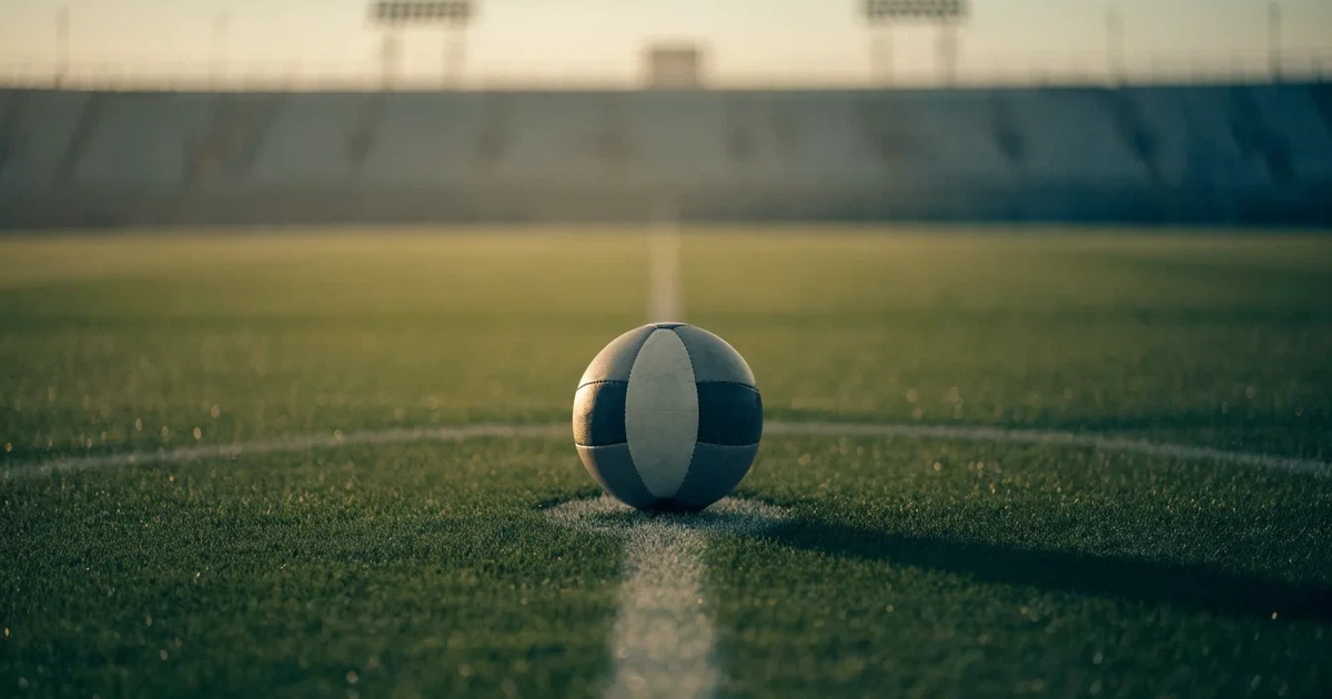 Un pallone da calcio sul dischetto del centrocampo di un prato, alla luce del mattino